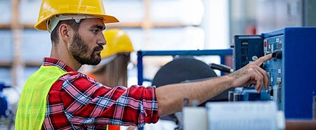 An industrial worker in a factory pushing a button.