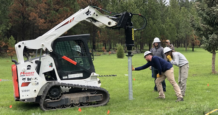 Constrution workers using a machine mounted haudralic driver.